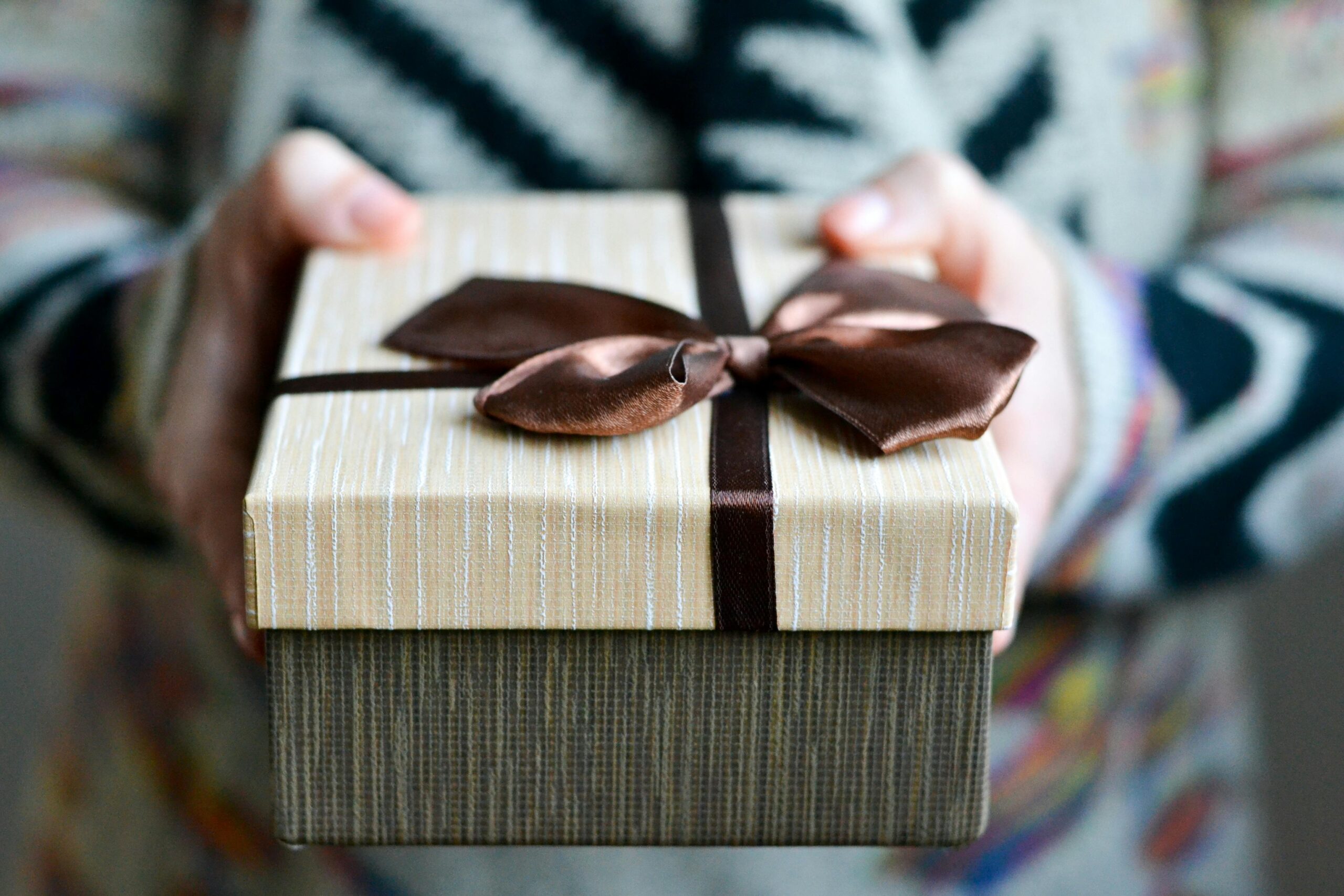 Stylish gift box with brown ribbon held in hands, perfect for holidays and celebrations.